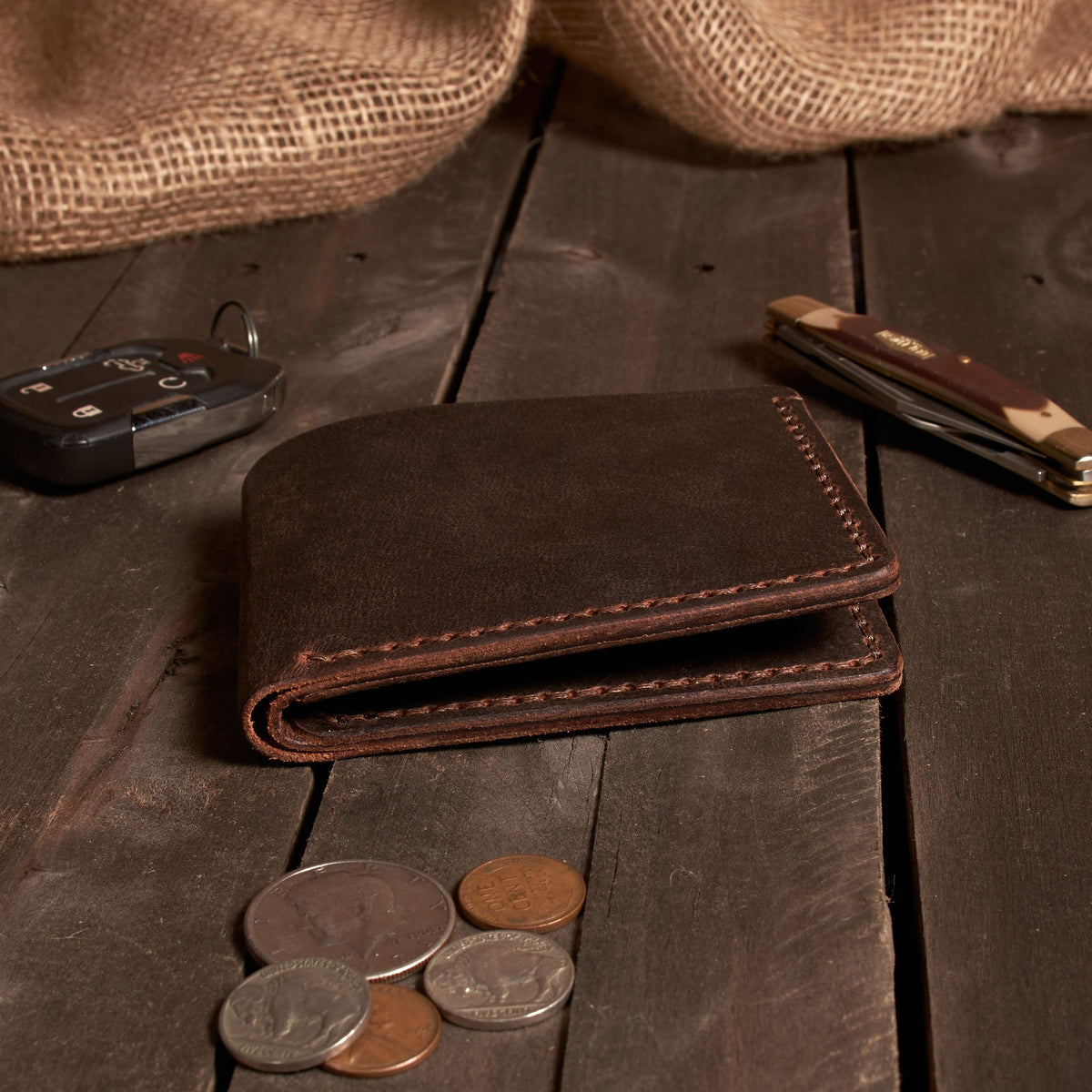 Brown leather wallet with coins on a wooden surface
