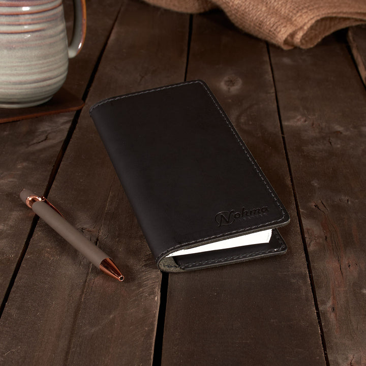 Black leather Checkbook Cover with a pen on a wooden surface