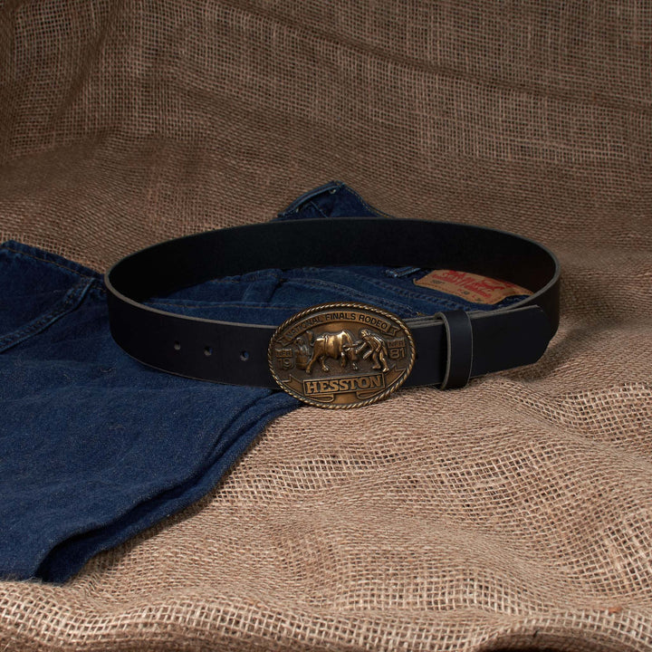 Black belt with a gold buckle on blue jeans against a brown fabric background