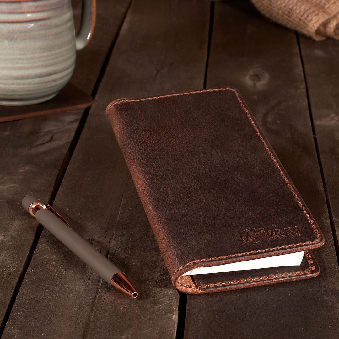 Brown leather Checkbook Cover with pen on a wooden surface