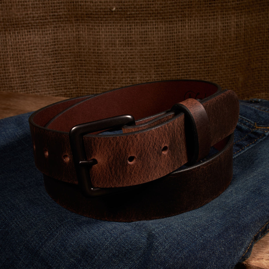 Brown leather belt on a denim surface with a brown textured background