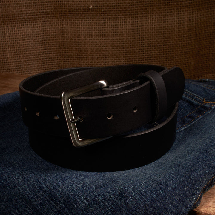 Black belt with silver buckle on a denim surface