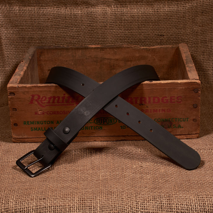 Black leather belt with a metal buckle on a rustic wooden crate background
