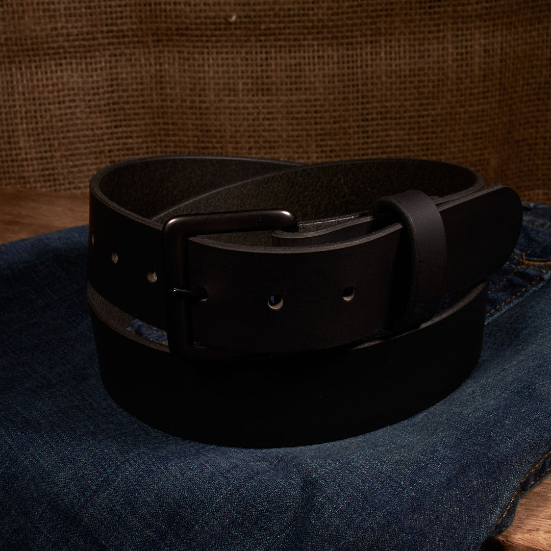 Black leather belt on a denim surface with a brown textured background