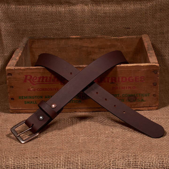 Brown leather belt with a metal buckle on a rustic wooden crate background
