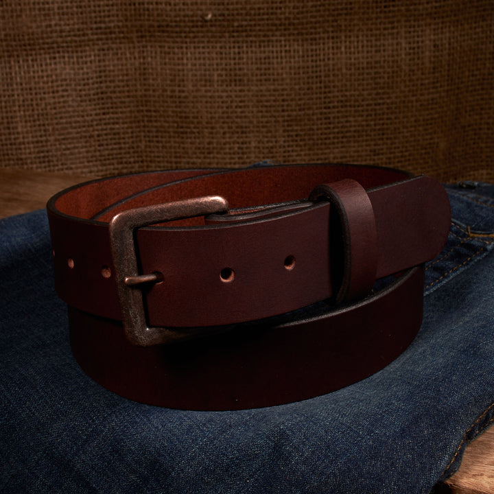 Brown leather belt with a metal buckle on a denim surface