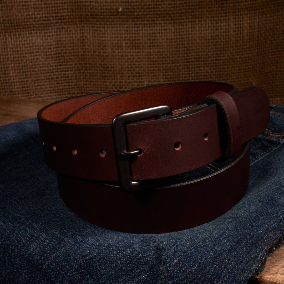 Brown leather belt with a silver buckle on a denim surface