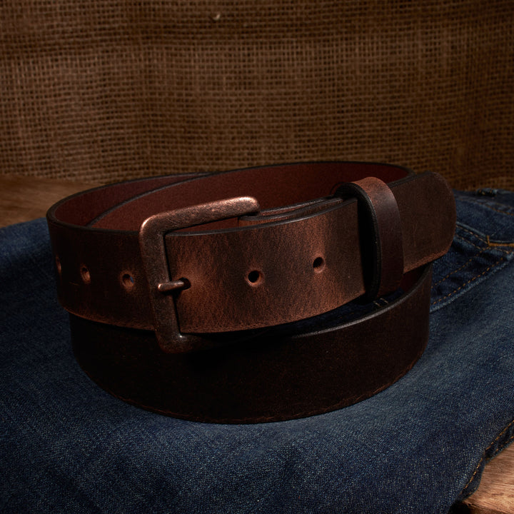 Brown leather belt with a metal buckle on a denim surface