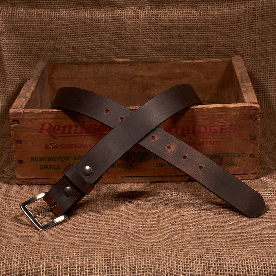 Brown leather belt with silver buckle on a wooden crate background