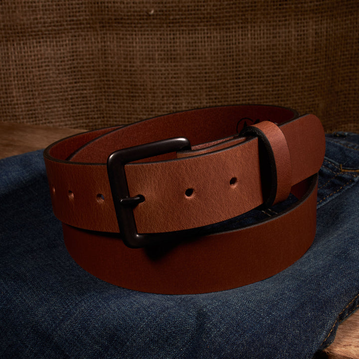 Brown leather belt with a black buckle on denim fabric