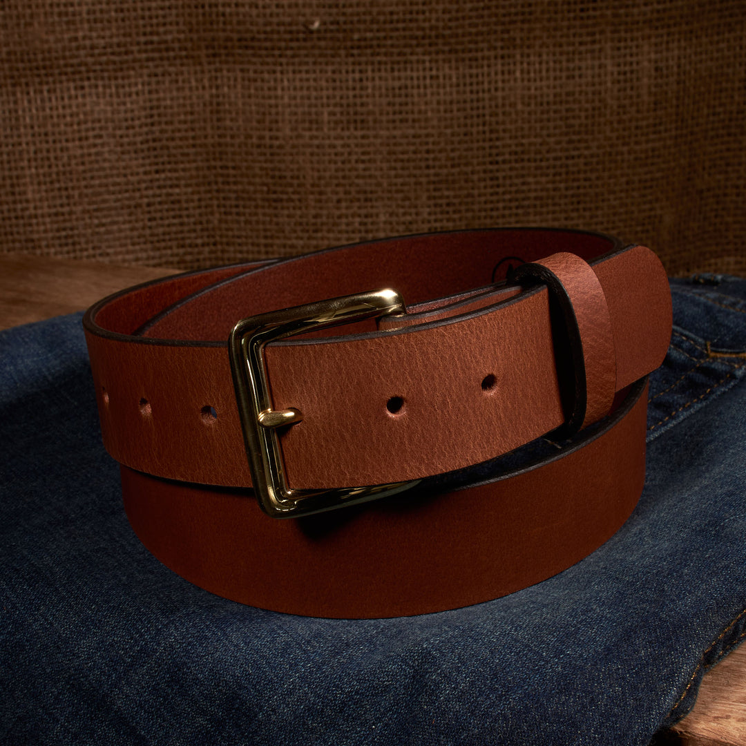 Brown leather belt with a gold buckle on a denim background