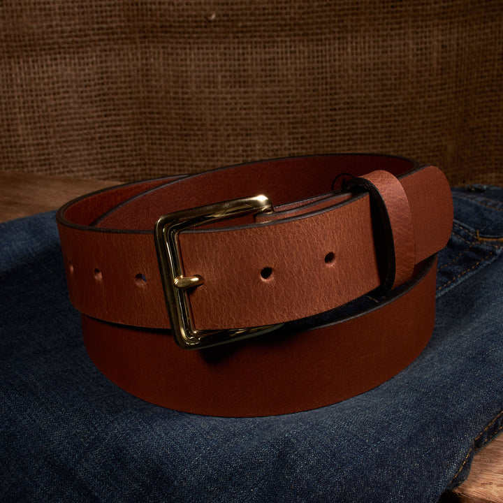 Brown leather belt with a gold buckle on a denim background