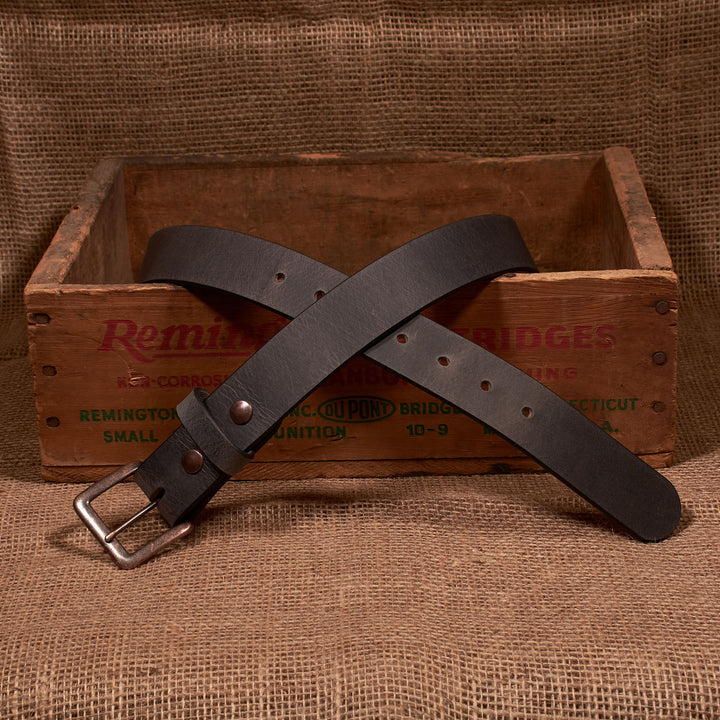 Brown leather belt with a silver buckle on a rustic wooden box and burlap background