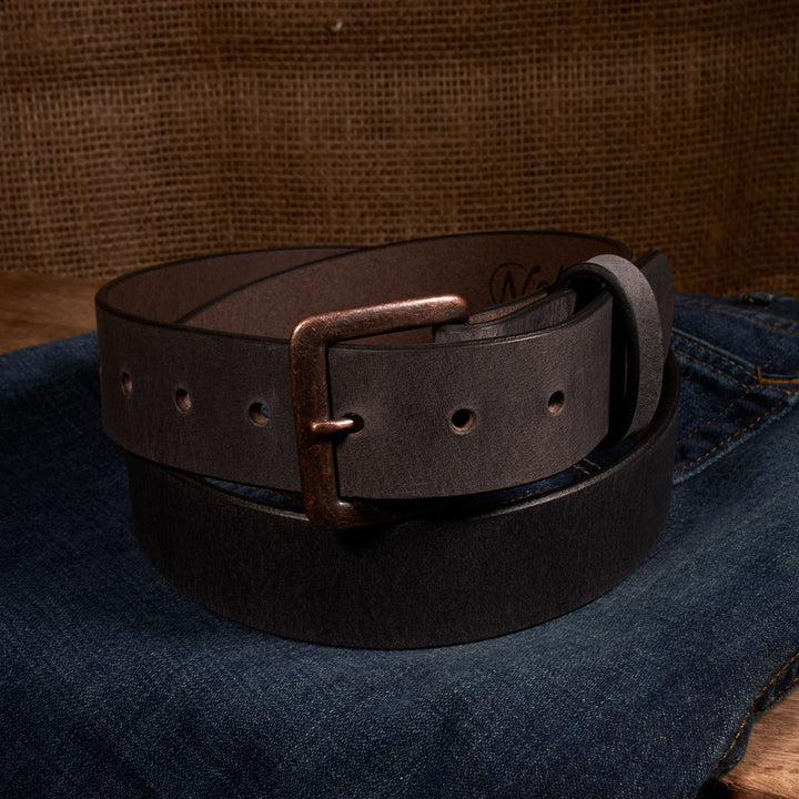 Brown leather belt with a brass buckle on a denim surface