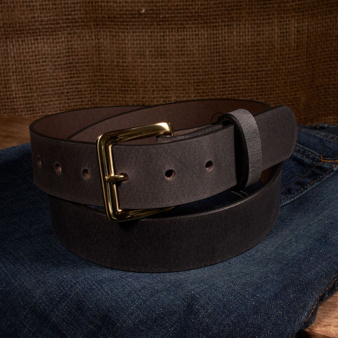 Brown leather belt with gold buckle on a denim surface