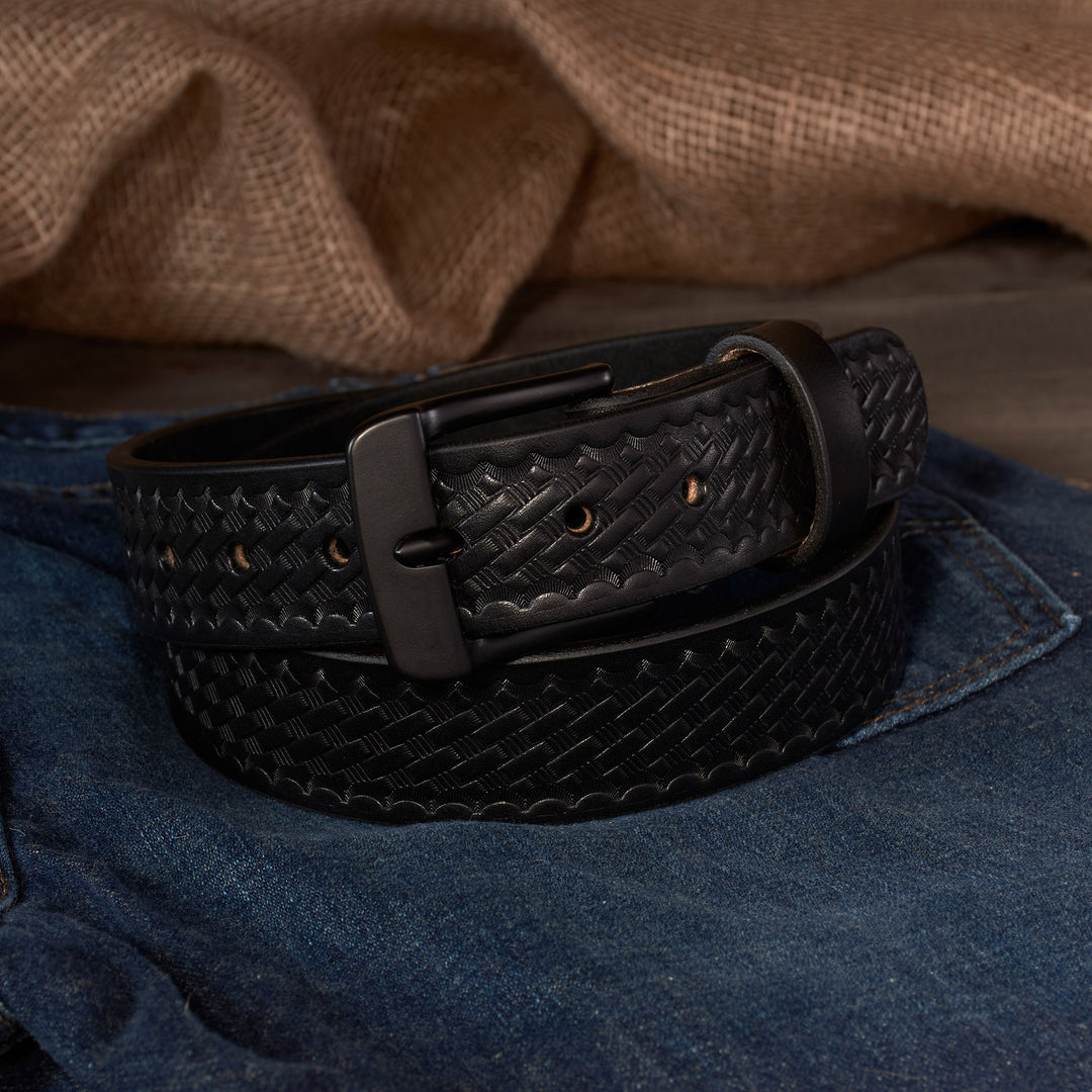 Black basketweave leather belt on a denim surface with a brown fabric background