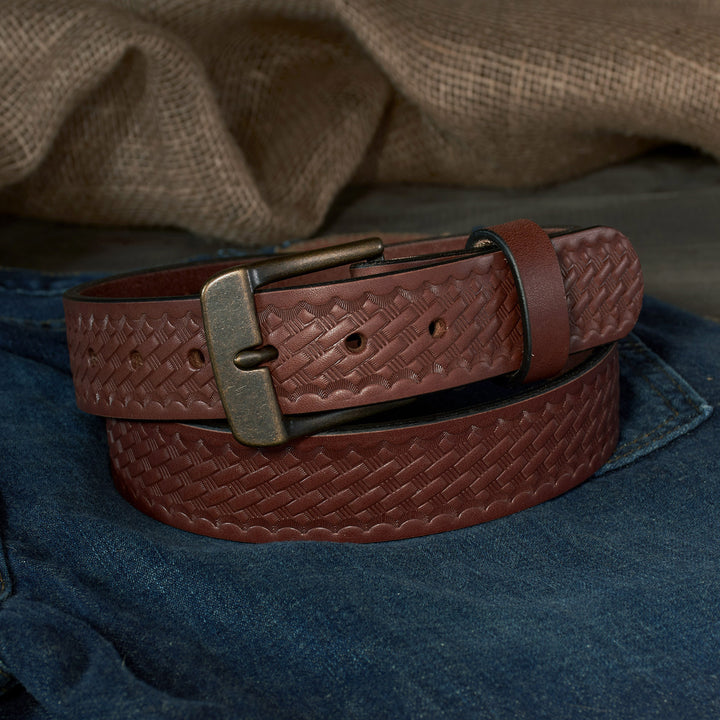 Brown leather belt with a textured pattern and brass buckle on a denim surface.