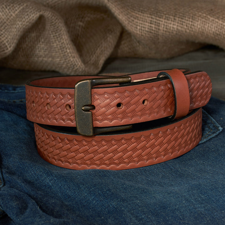 Brown leather belt with basketweave pattern and brass buckle on blue fabric