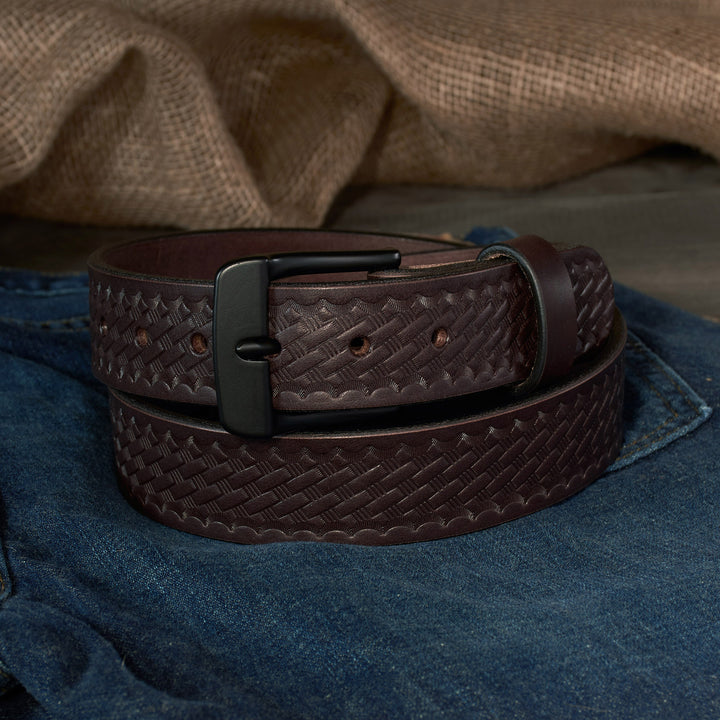 Brown basketweave leather belt with a black buckle on blue jeans.