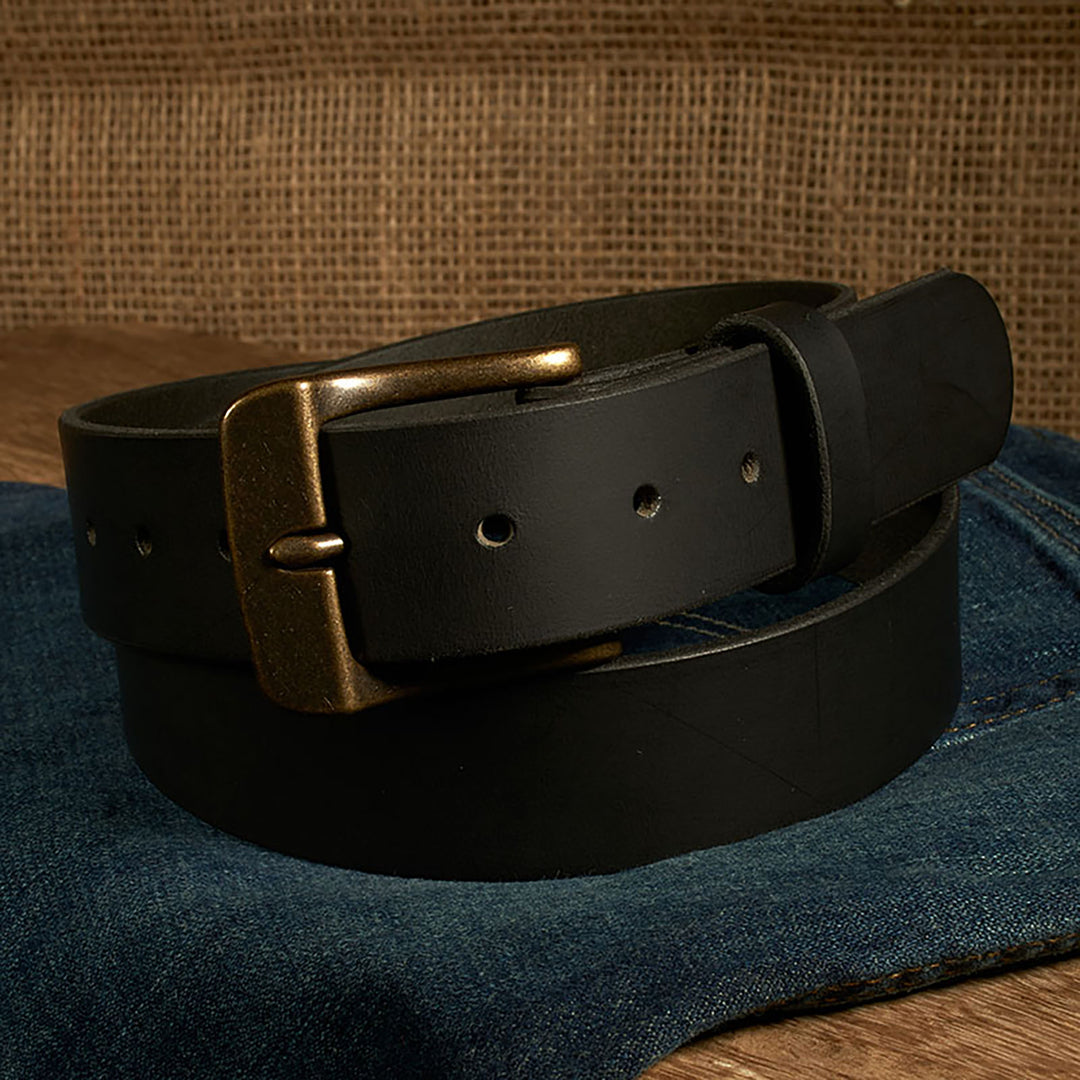 Black leather belt with brass buckle on a denim surface