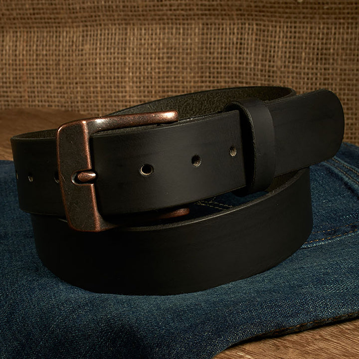 Black leather belt with a bronze buckle on a denim surface