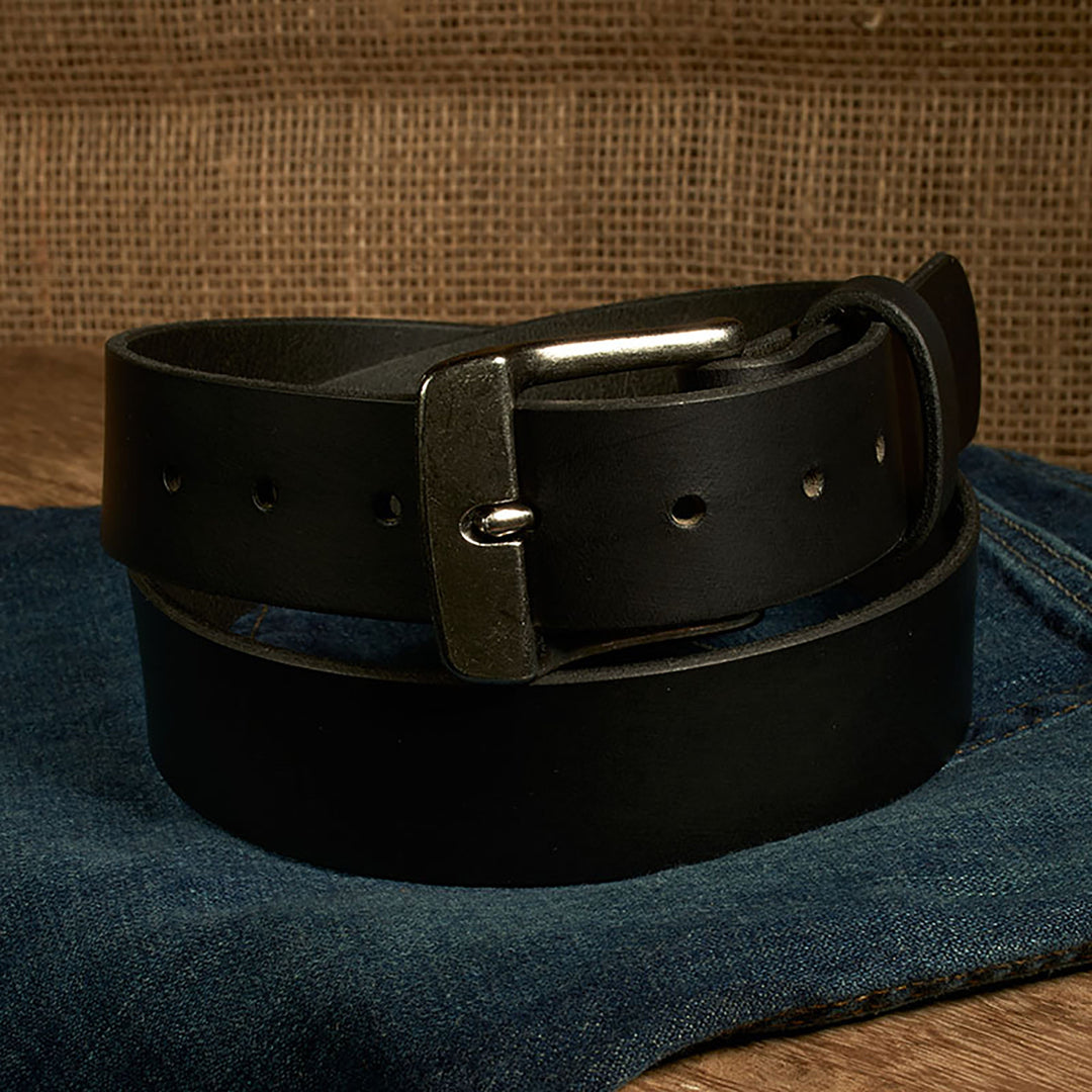 Black leather belt with a silver buckle on a denim surface