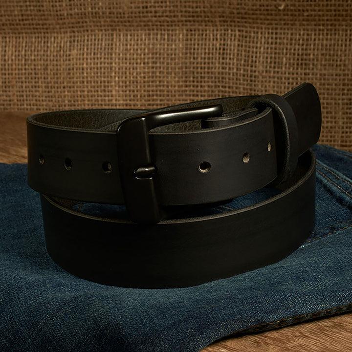 Black leather belt on a denim surface with a brown fabric background