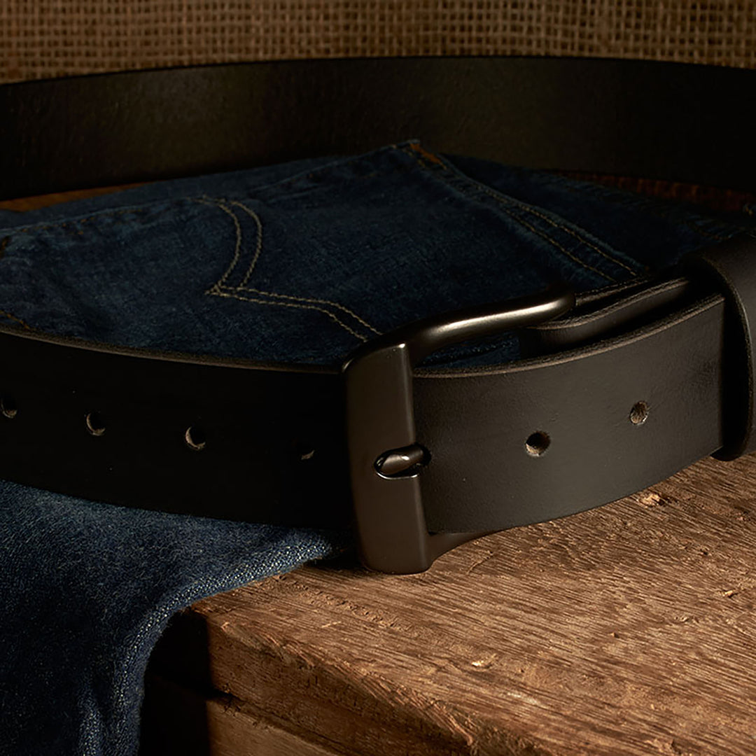 Black belt on a pair of blue jeans on a wooden surface