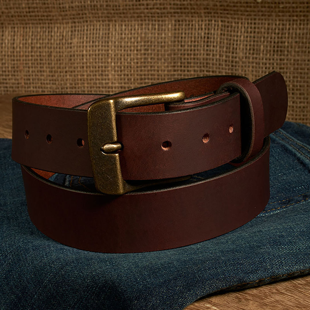 Brown leather belt with brass buckle on a denim surface