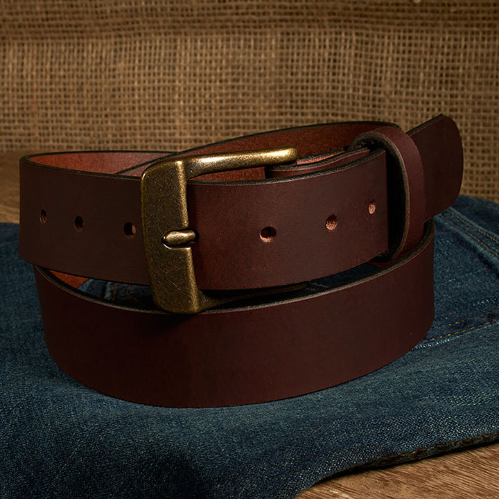 Brown leather belt with brass buckle on a denim surface