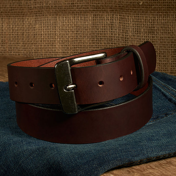Brown leather belt with a silver buckle on a denim surface