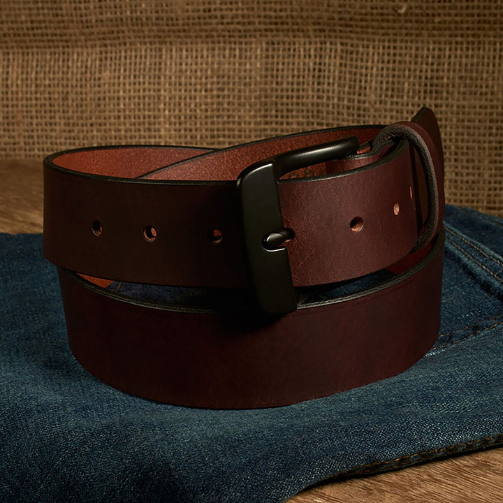 Brown leather belt with a black buckle on a denim surface