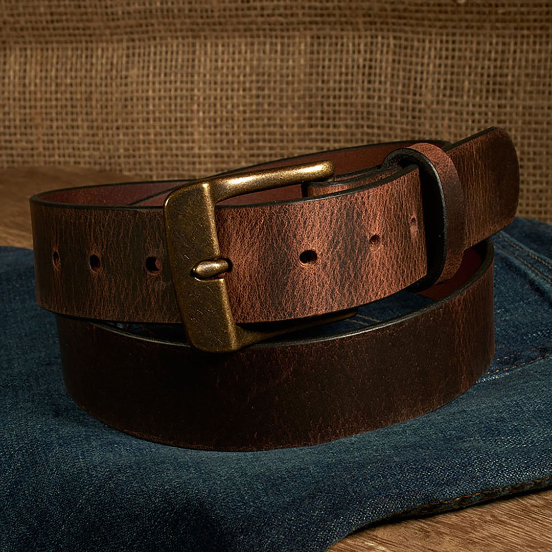 Brown leather belt with brass buckle on a denim surface