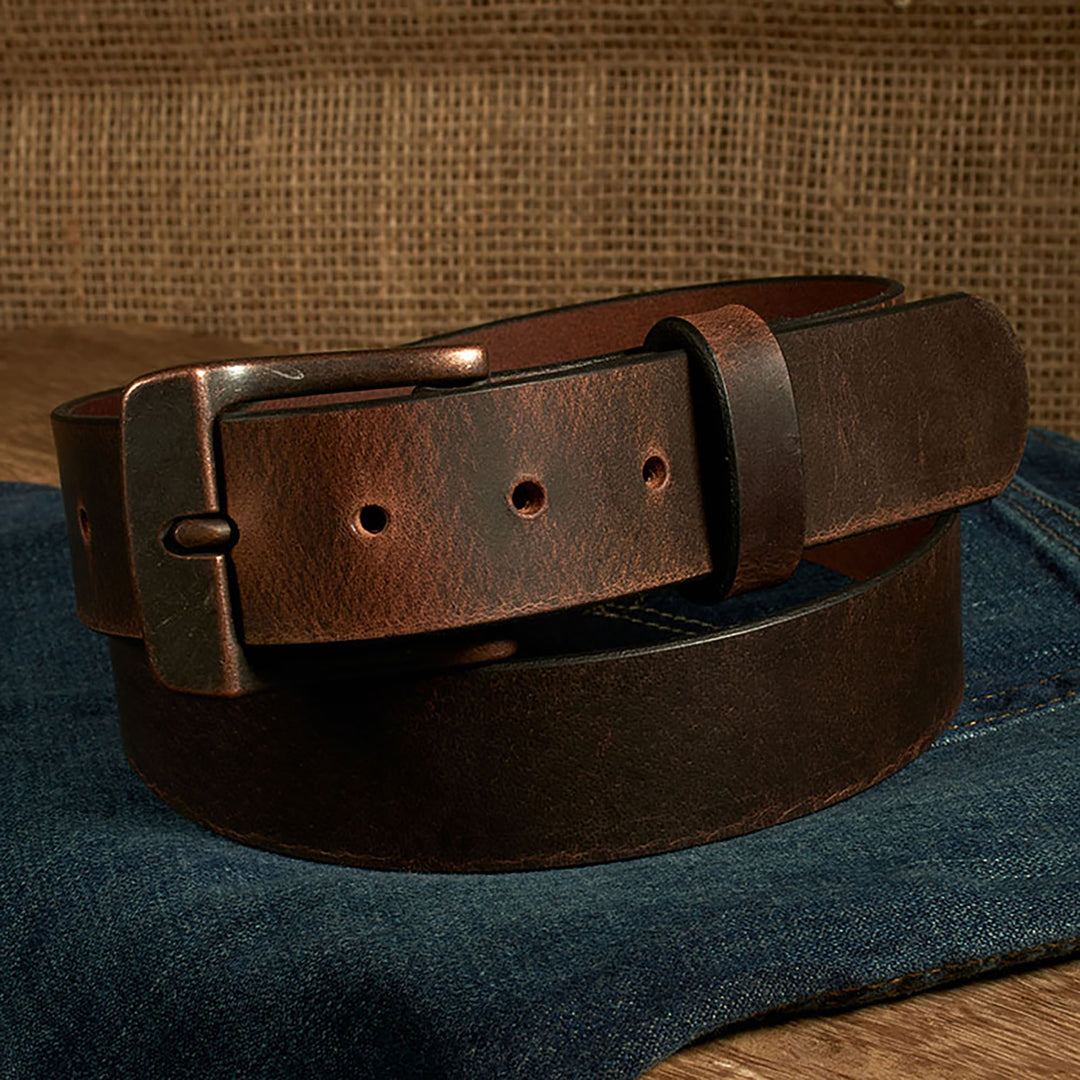 Brown leather belt with a metal buckle on a denim surface
