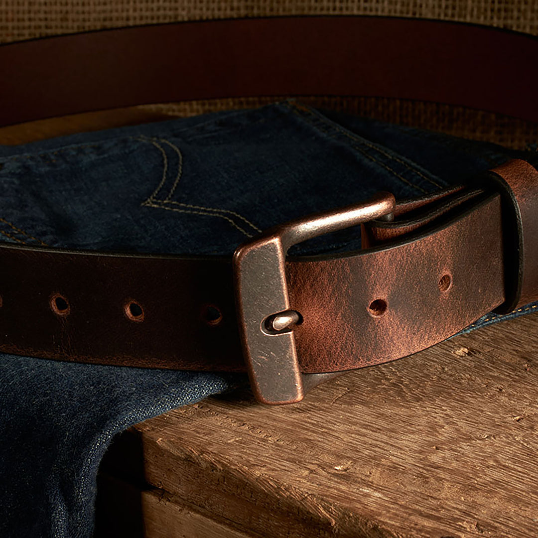 Brown leather belt with brass buckle on a denim fabric background