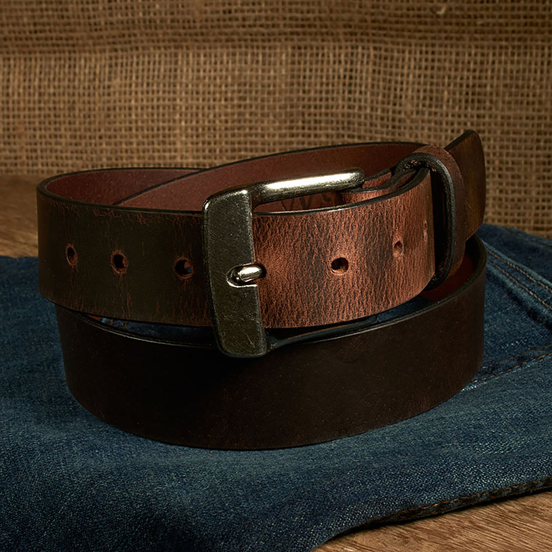 Brown leather belt with a silver buckle on a denim surface