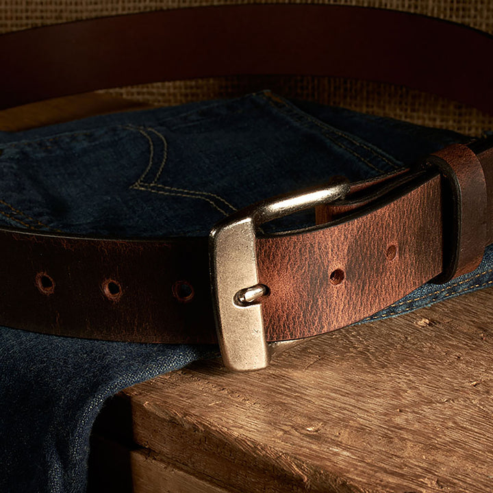 Brown leather belt with silver buckle on a denim fabric background