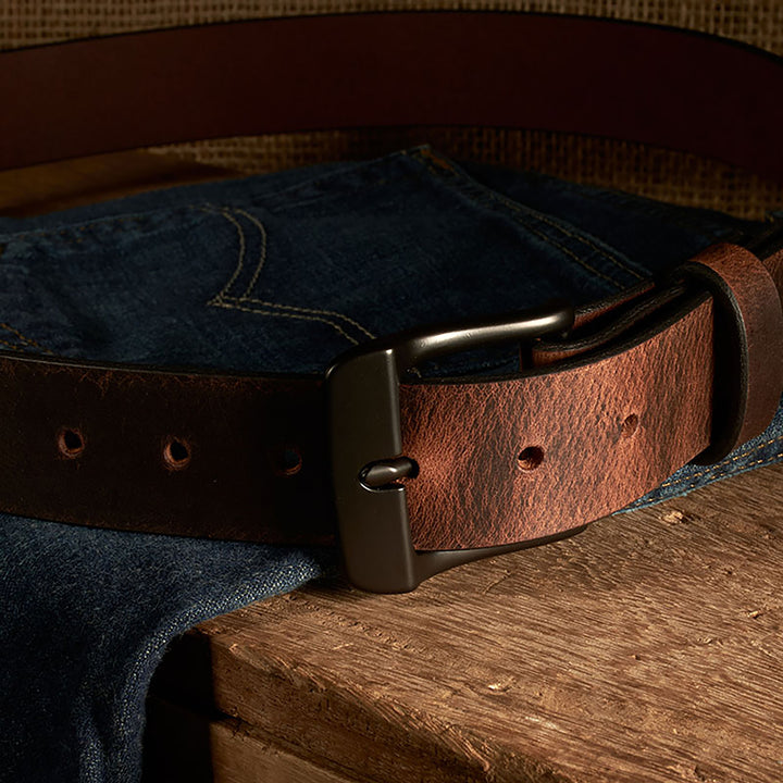 Brown leather belt with metal buckle on a denim fabric background
