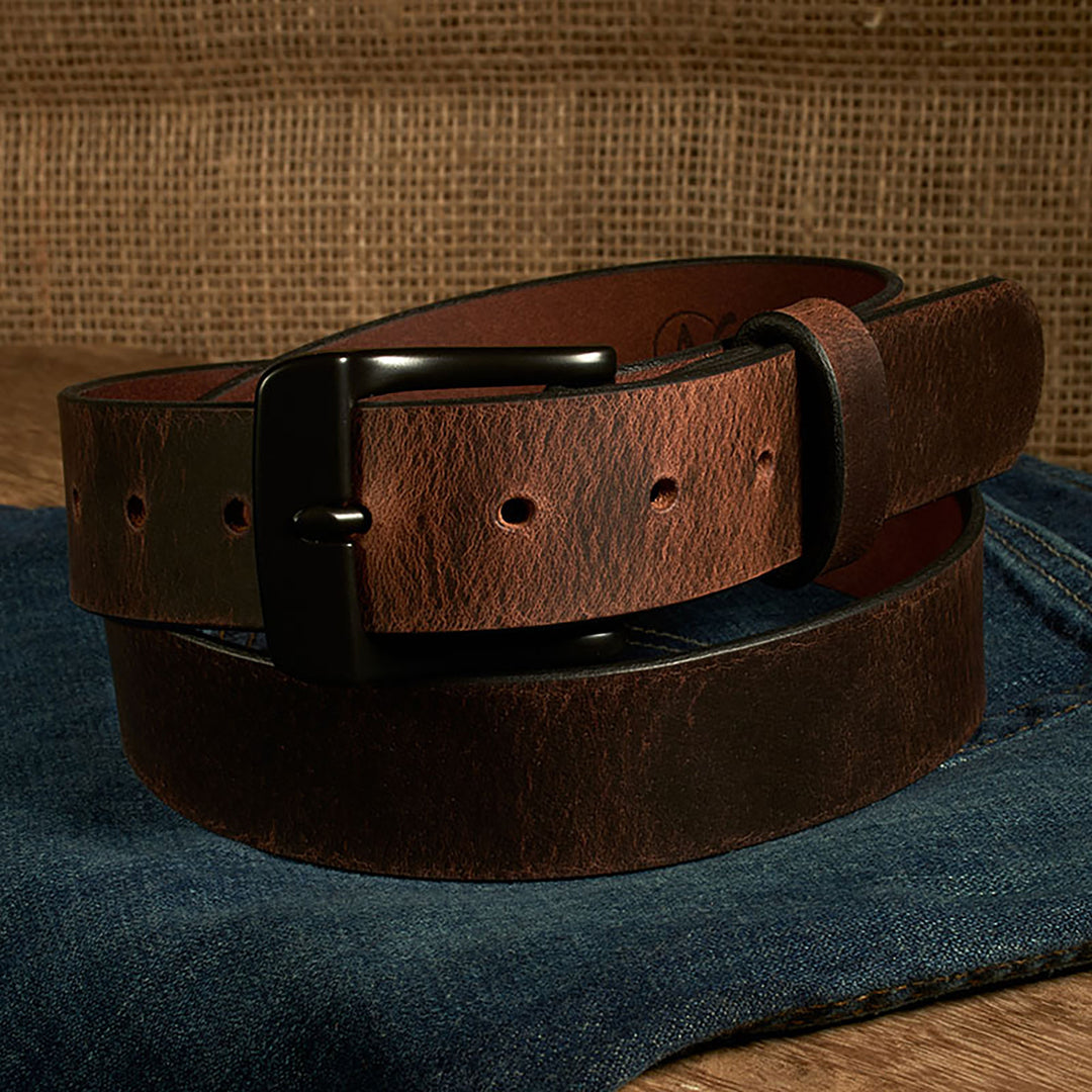 Brown leather belt with black buckle on a denim surface