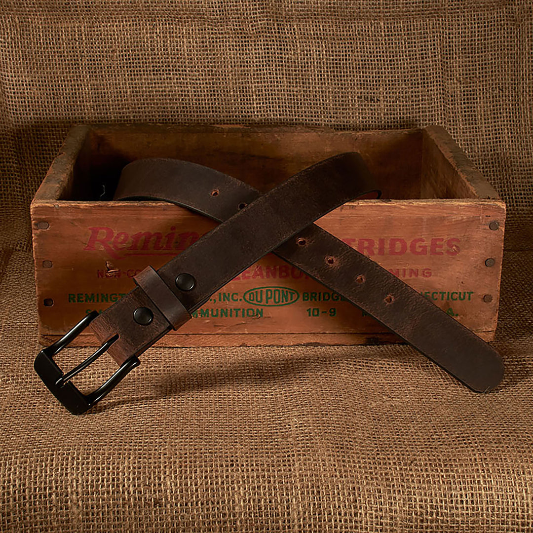 Brown leather belt with black buckle on a wooden crate against a burlap background