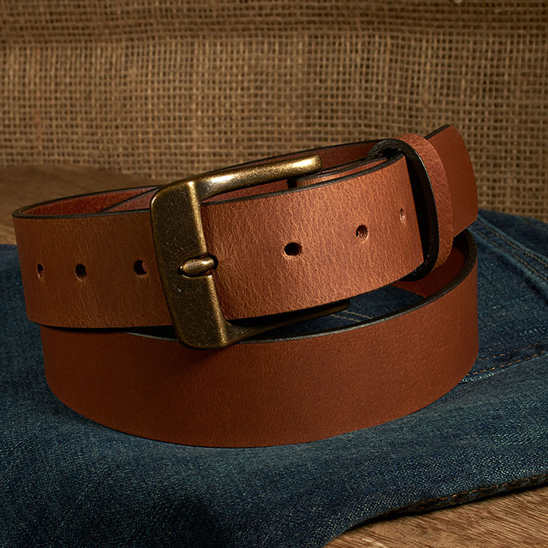 Brown leather belt with brass buckle on a denim surface