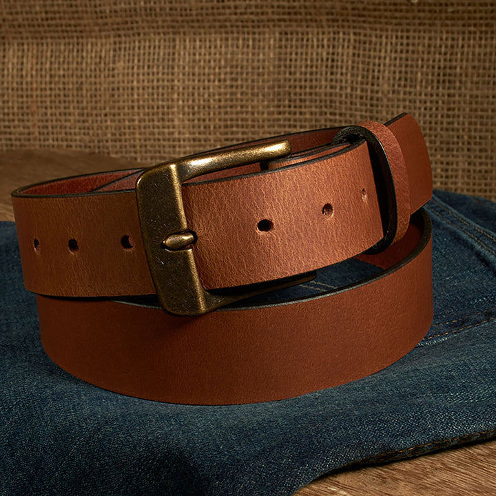 Brown leather belt with brass buckle on a denim surface