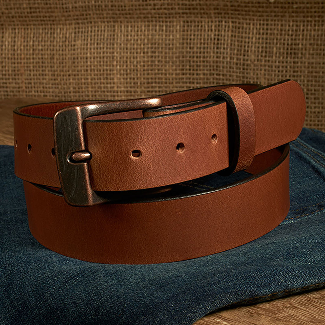 Brown leather belt with a bronze buckle on a denim surface