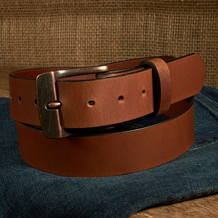 Brown leather belt with a bronze buckle on a denim surface