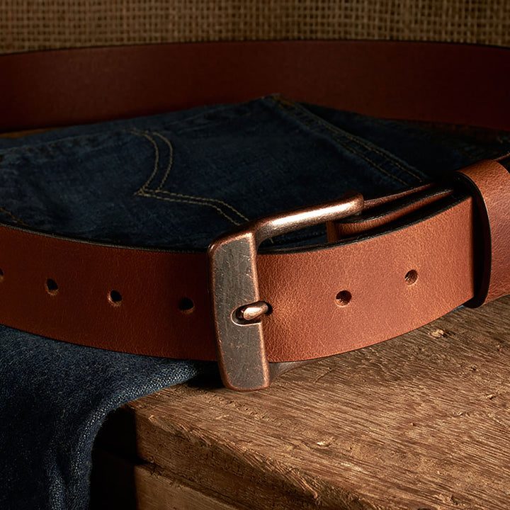 Brown leather belt with brass buckle on a denim fabric background