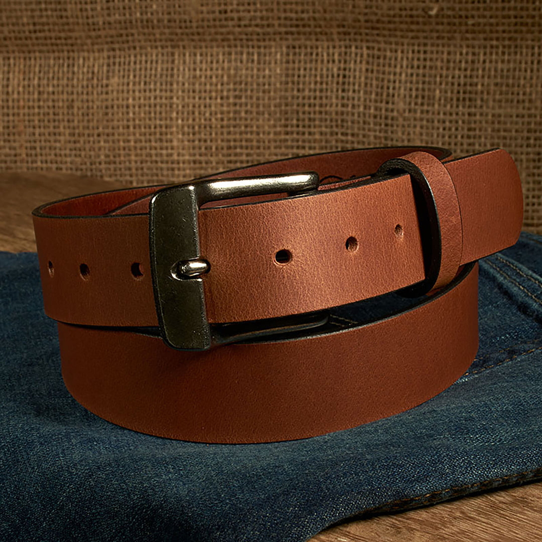 Brown leather belt with a silver buckle on a denim surface