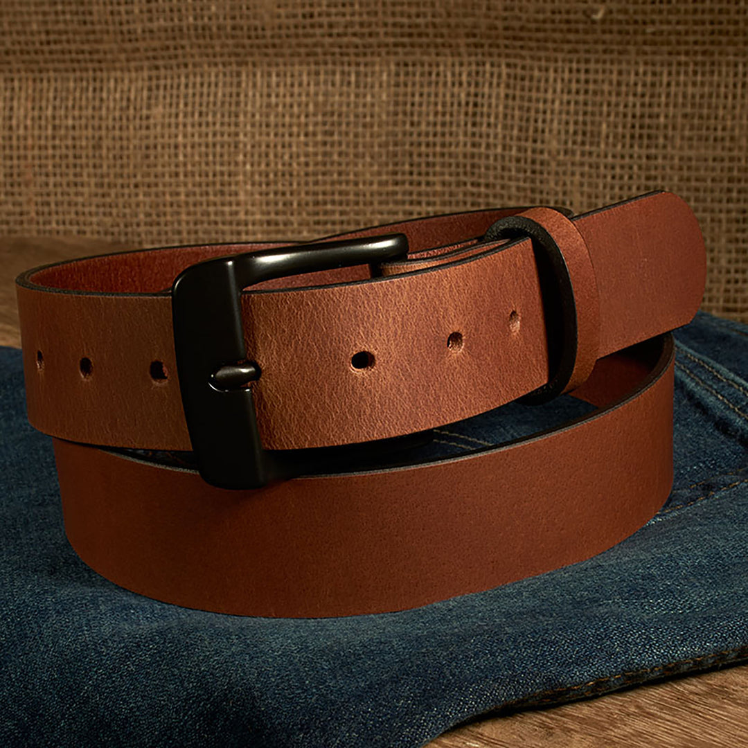 Brown leather belt with a black buckle on a denim surface