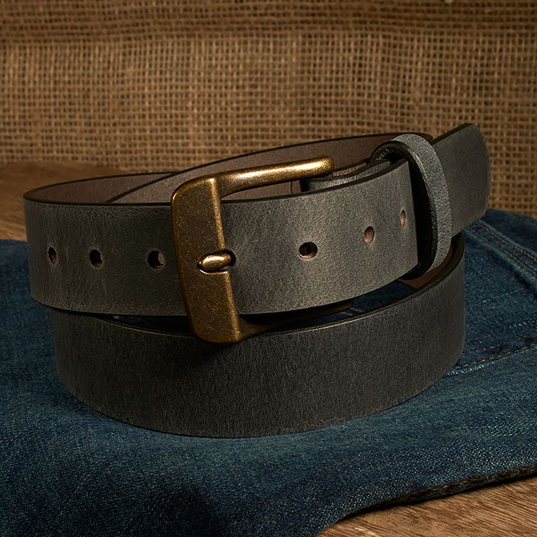 Black leather belt with brass buckle on a denim surface