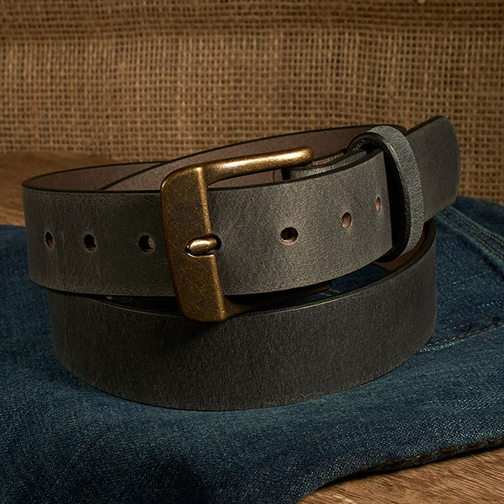 Black leather belt with brass buckle on a denim surface