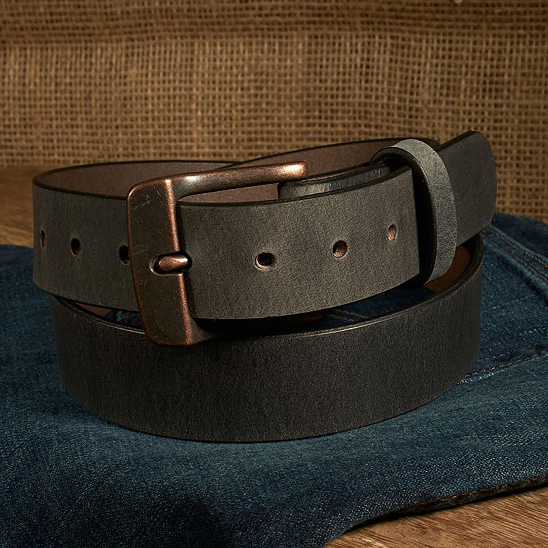 Black leather belt with a bronze buckle on a denim surface
